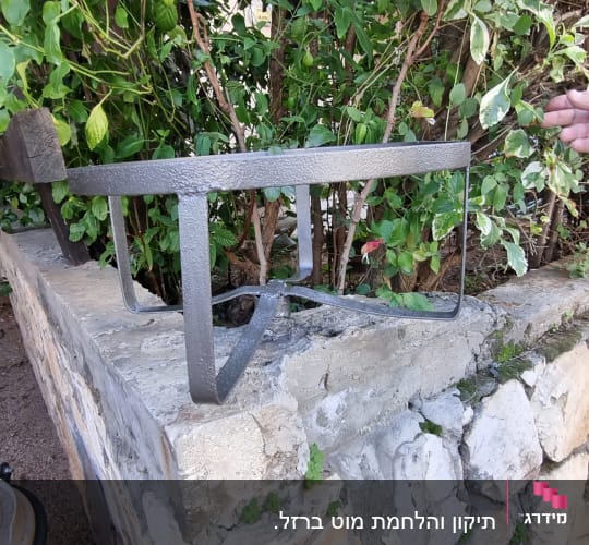 מסגרת מתכת על קיר אבן עם צמחייה